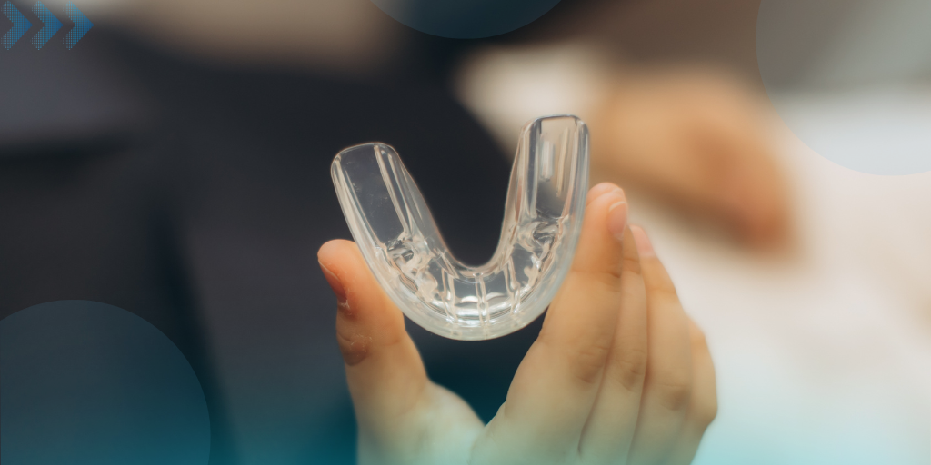 Hand holding a clear custom mouthguard for nighttime teeth grinding