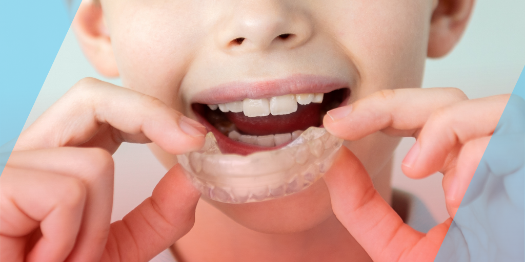 Child holding a clear Invisalign aligner.