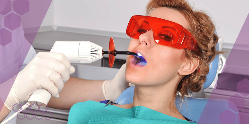Patient wearing protective glasses while a dentist hardens a composite filling with a curing light