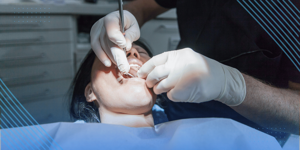 Gloved dentist using instruments during a tooth extraction procedure