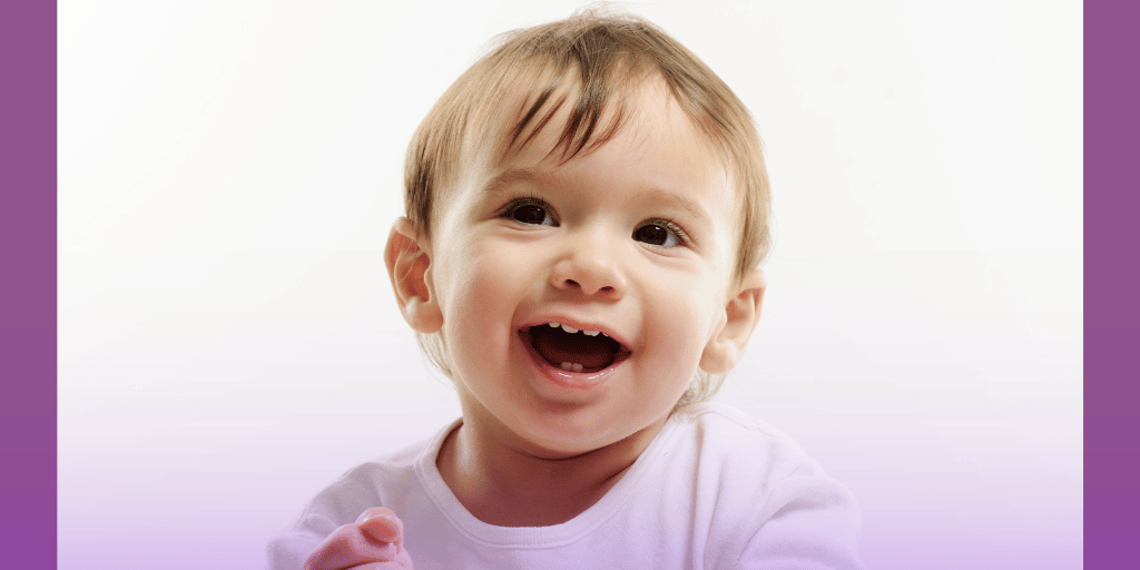 Smiling toddler showing new baby teeth around the age of a first dental visit